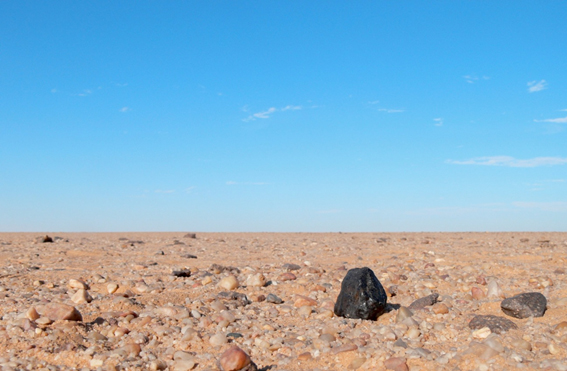 図４：スーダンのヌベア砂漠で見つかったAlmahata Sitta隕石（画面やや左下の黒い塊）。画像：NASA。